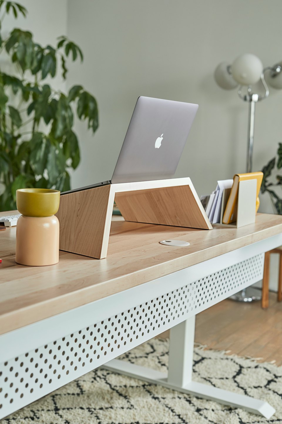 Laptop on a light wood stand on a modern desk.